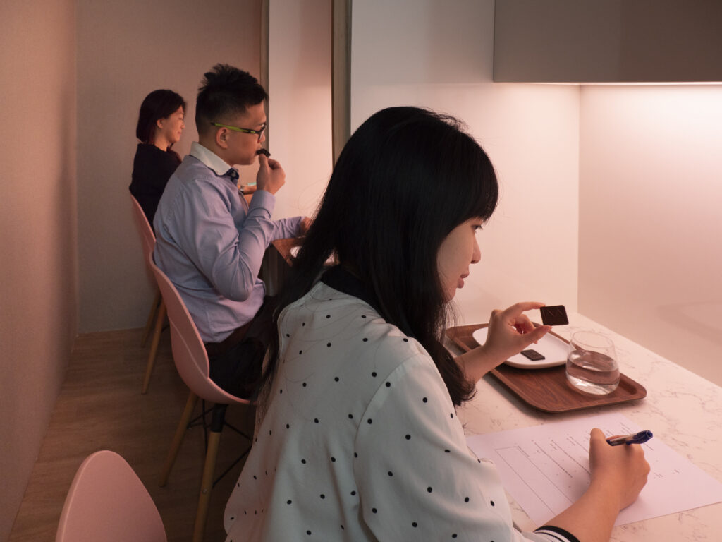 Shows a lab with mood lighting where new products are tested by a panel