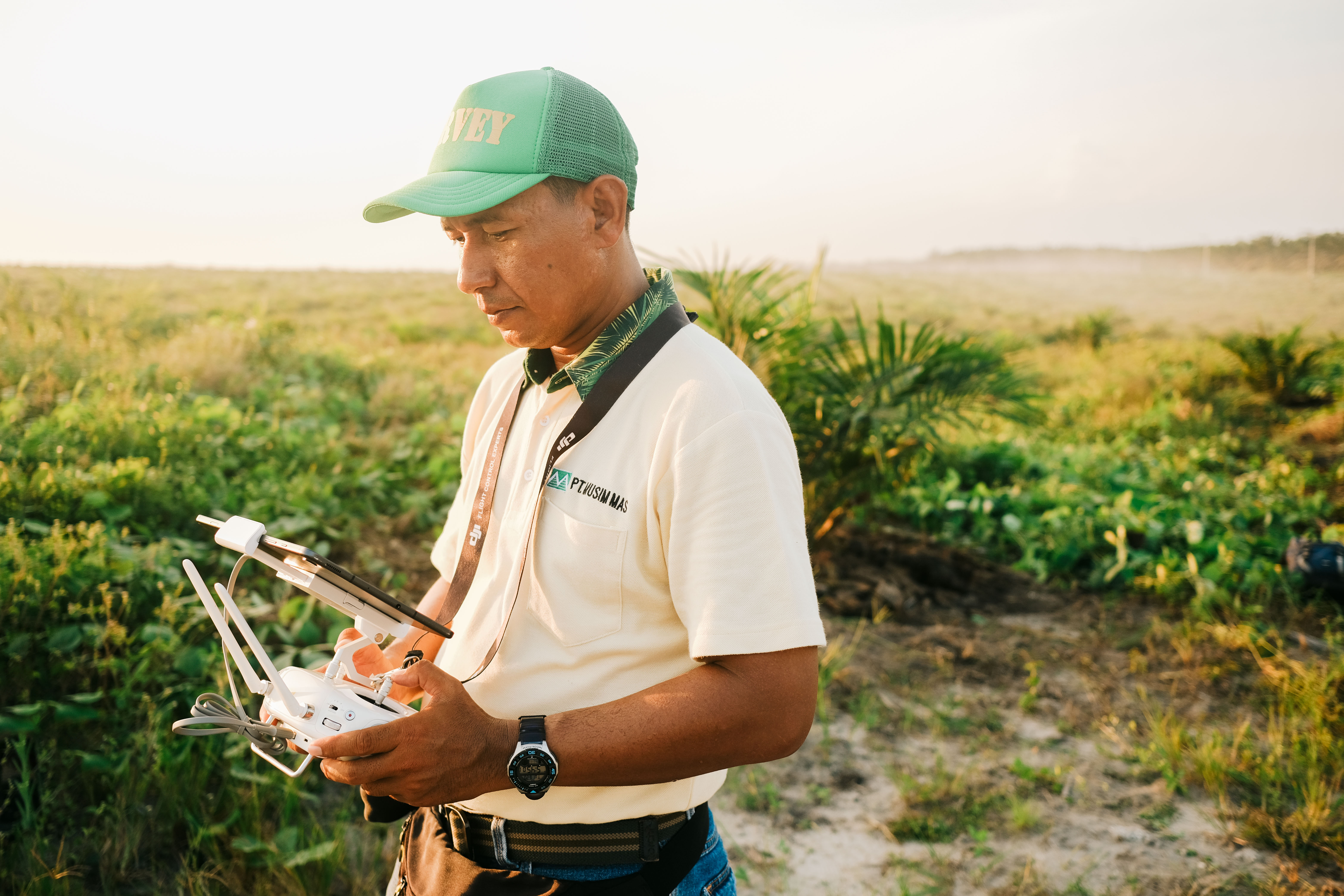 Musim Mas GIS staff looking at his handheld device to control the drone and assess the hotspot.